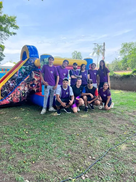 Equipe da Festa Top com camisetas roxas ao lado de um brinquedo inflável