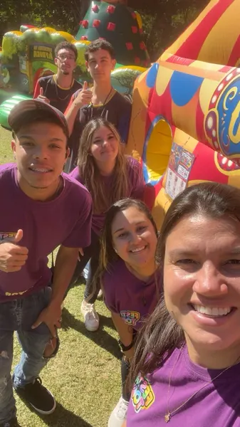 Integrantes da equipe Festa Top de camiseta roxa sorrindo em uma festa